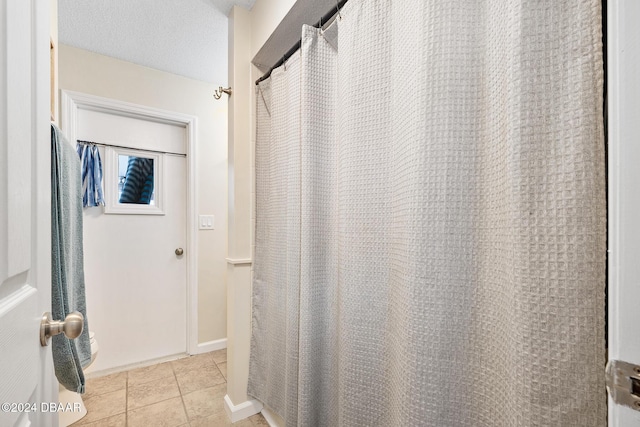 bathroom with tile patterned floors, curtained shower, and a textured ceiling