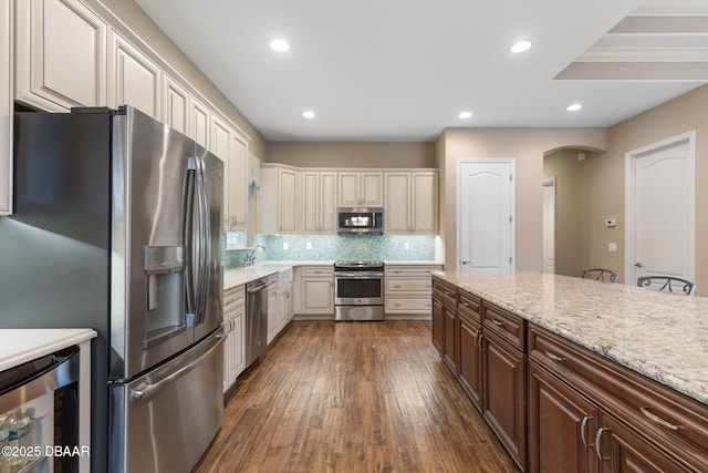 kitchen with stainless steel appliances, dark brown cabinetry, tasteful backsplash, beverage cooler, and dark hardwood / wood-style floors