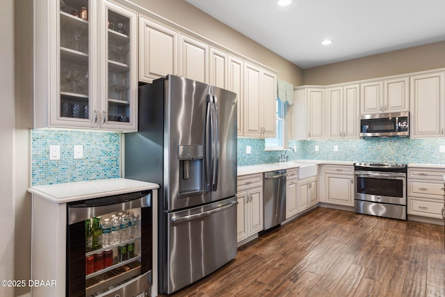 kitchen featuring sink, backsplash, beverage cooler, dark hardwood / wood-style floors, and stainless steel appliances