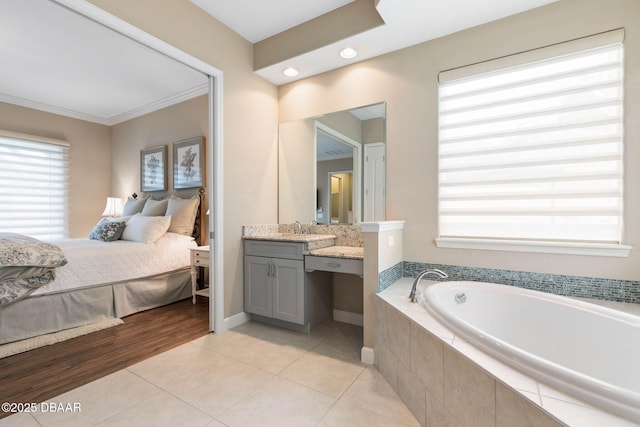 bathroom with crown molding, tile patterned flooring, vanity, and a relaxing tiled tub