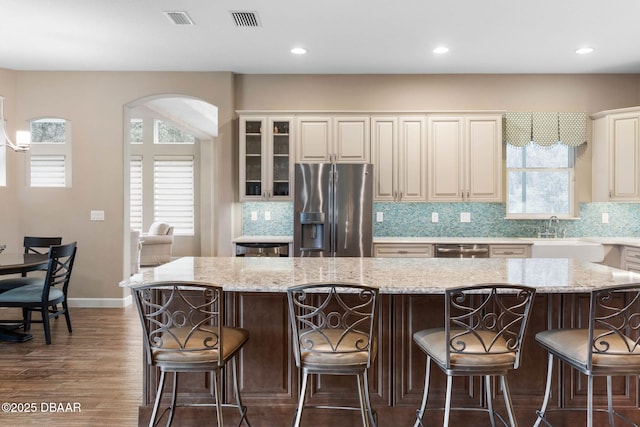 kitchen featuring a large island, light stone countertops, sink, appliances with stainless steel finishes, and a breakfast bar area