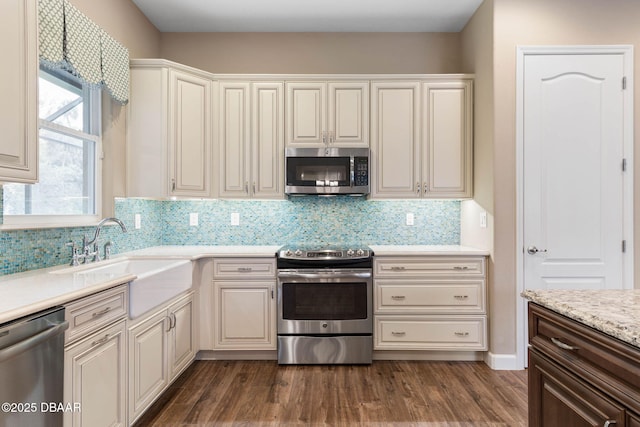 kitchen with appliances with stainless steel finishes, sink, backsplash, and dark wood-type flooring