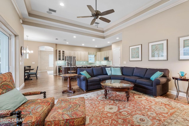 living room featuring crown molding, light hardwood / wood-style floors, and a raised ceiling