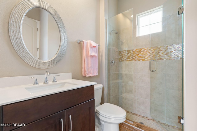 bathroom featuring toilet, vanity, and an enclosed shower