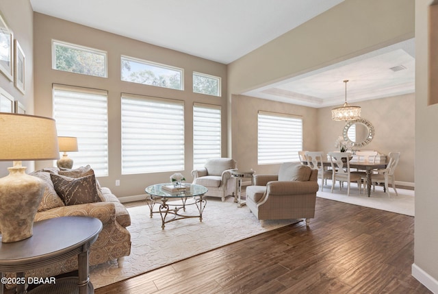 living room featuring a tray ceiling, a chandelier, and dark hardwood / wood-style floors