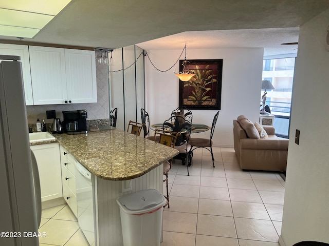 kitchen with white cabinetry, white appliances, light stone countertops, and kitchen peninsula