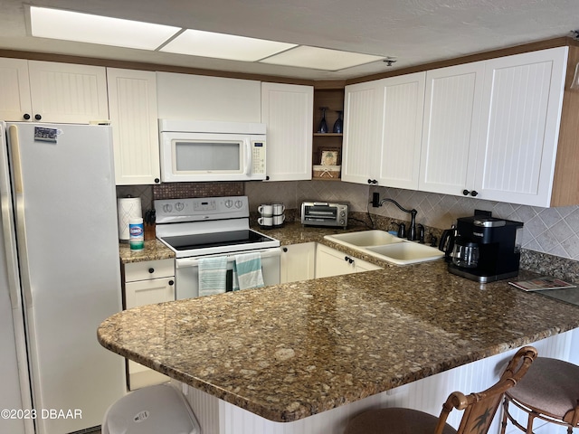 kitchen featuring white cabinetry, kitchen peninsula, sink, and white appliances