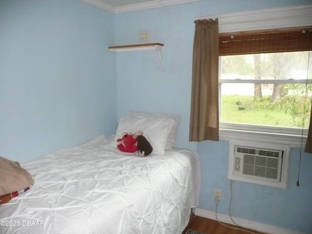 bedroom with a wall unit AC, crown molding, baseboards, and wood finished floors