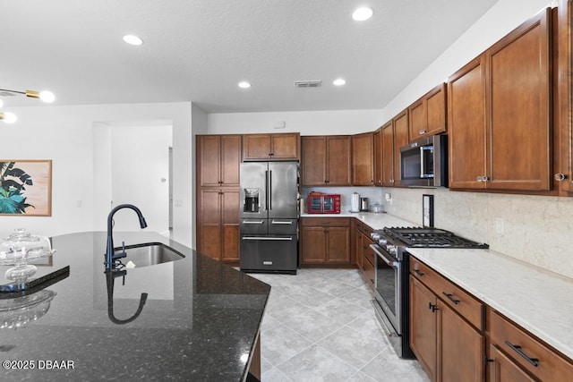 kitchen with light tile patterned flooring, sink, tasteful backsplash, high quality appliances, and dark stone counters