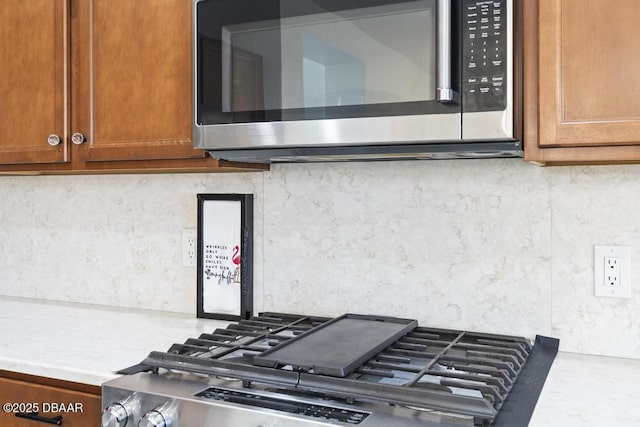 interior details featuring backsplash and range with gas cooktop