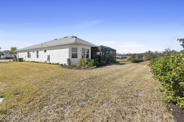 view of side of home featuring a yard and glass enclosure