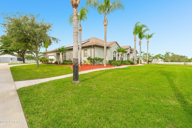 540 Leeway Trl, Ormond Beach, FL 32174 - view of front of home with roof mounted solar panels, an attached garage, a front yard, stucco siding, and driveway