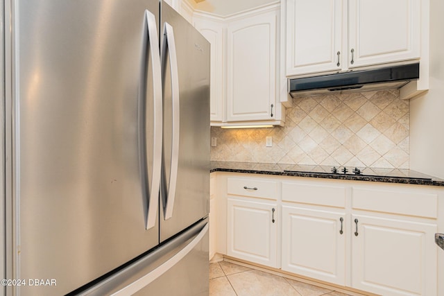 540 Leeway Trl, Ormond Beach, FL 32174 - kitchen with freestanding refrigerator, under cabinet range hood, light tile patterned flooring, tasteful backsplash, and dark stone countertops