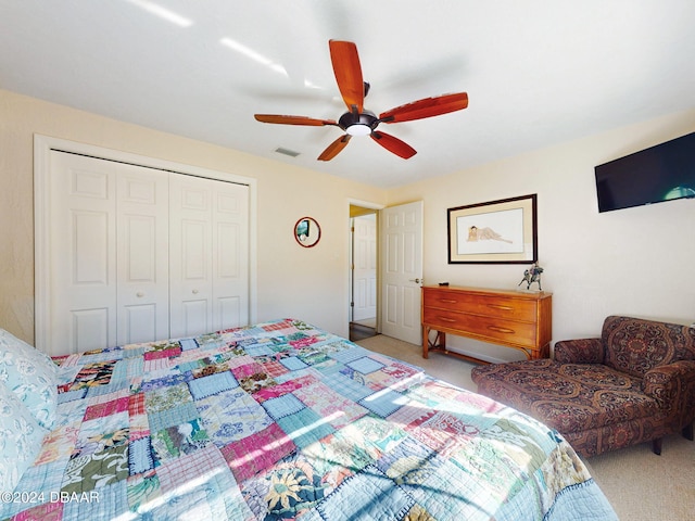 bedroom with ceiling fan, light carpet, and a closet