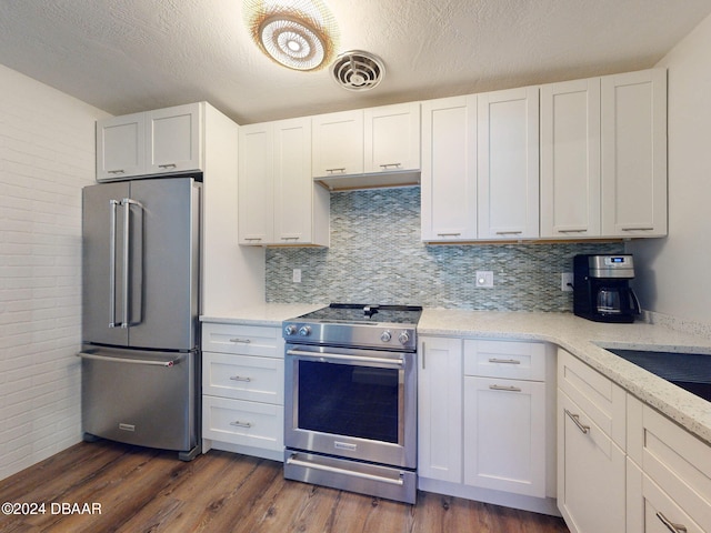 kitchen with light stone counters, white cabinetry, stainless steel appliances, and dark hardwood / wood-style floors