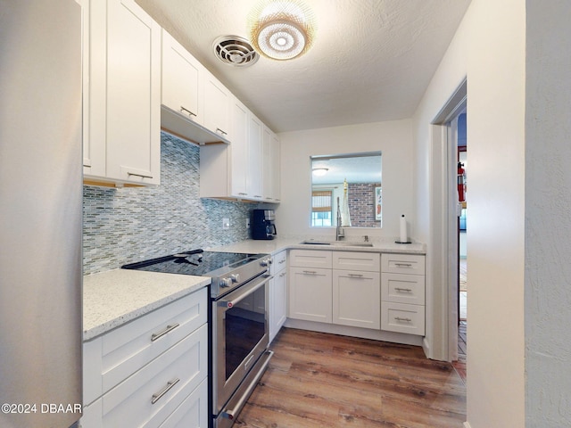 kitchen featuring white cabinetry, light hardwood / wood-style flooring, stainless steel electric stove, and sink