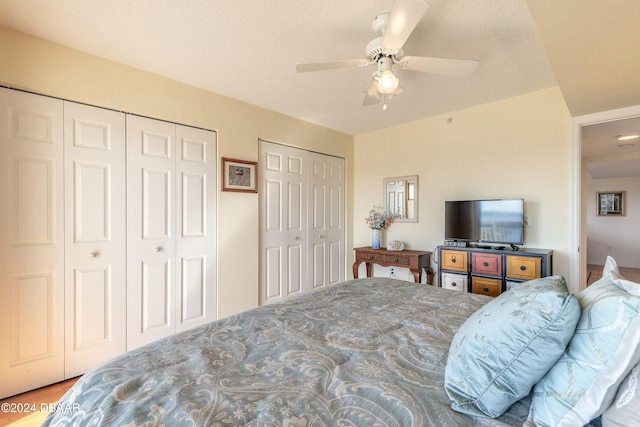 bedroom featuring a textured ceiling, ceiling fan, and two closets