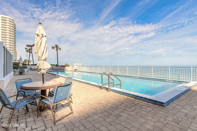 view of swimming pool with a patio area and a water view