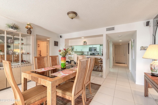 tiled dining space with a textured ceiling