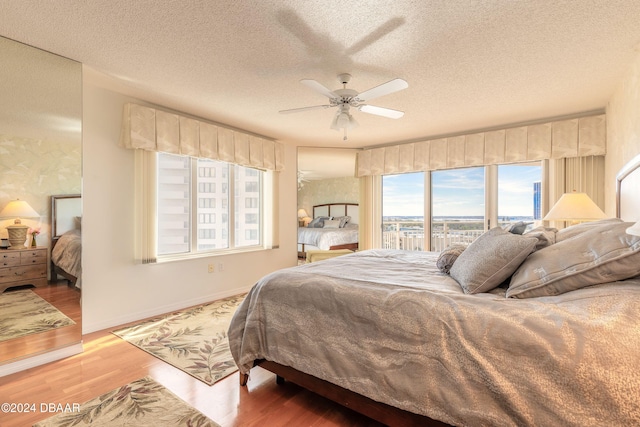 bedroom with a textured ceiling, ceiling fan, and hardwood / wood-style flooring