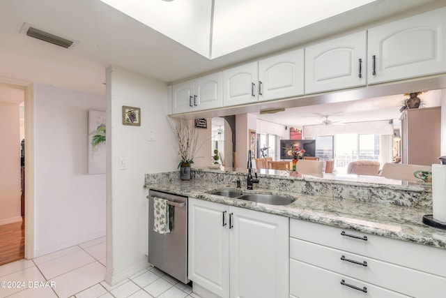 kitchen with light stone countertops, dishwasher, white cabinetry, sink, and light tile patterned flooring