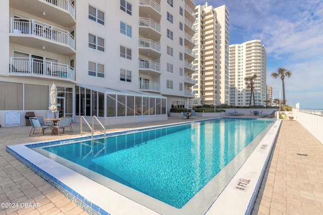 view of swimming pool featuring a patio area and a sunroom