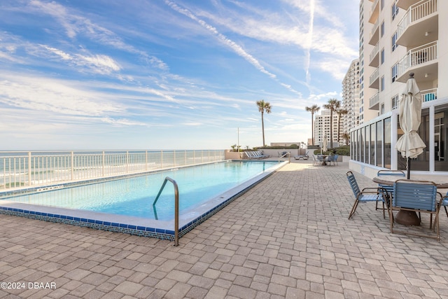 view of pool with a water view and a patio