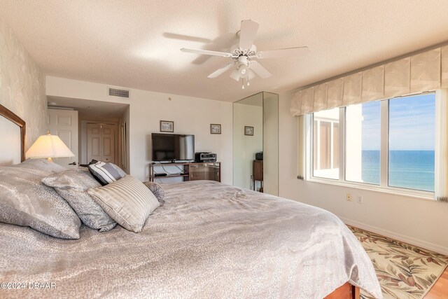 bedroom with ceiling fan and a textured ceiling