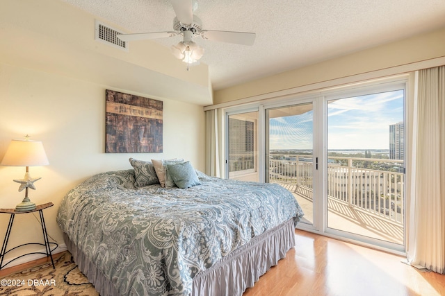 bedroom featuring access to outside, ceiling fan, a textured ceiling, and hardwood / wood-style flooring