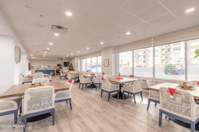 dining space featuring a paneled ceiling and light hardwood / wood-style flooring