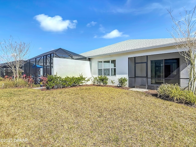 rear view of property featuring a yard and glass enclosure