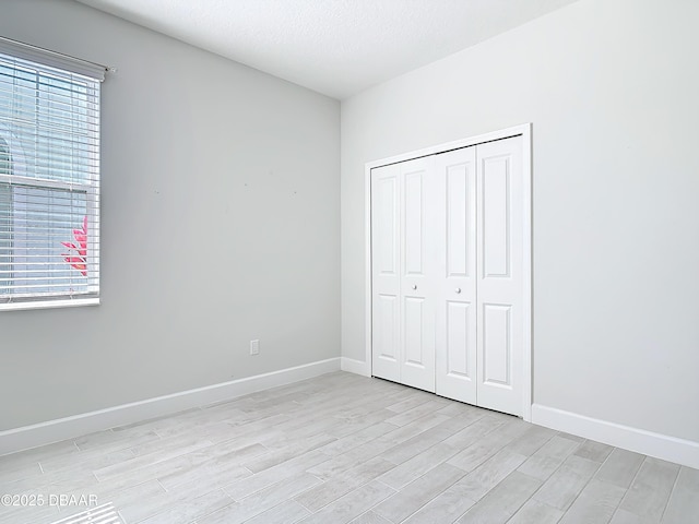 unfurnished bedroom with a closet, a textured ceiling, and light hardwood / wood-style flooring