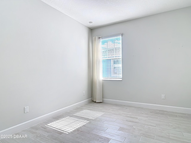 spare room with light hardwood / wood-style floors and a textured ceiling