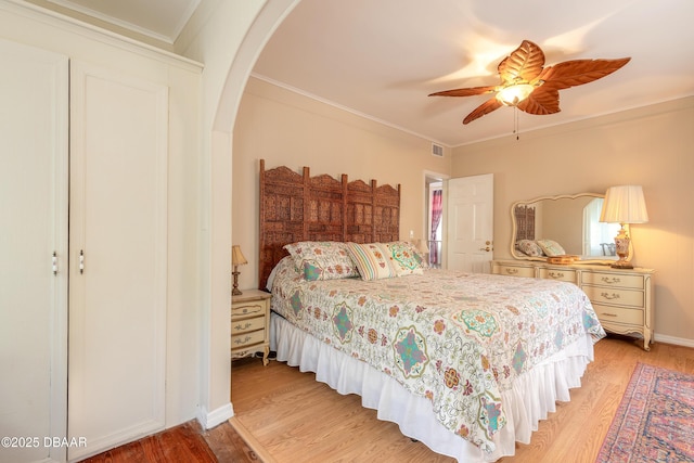 bedroom featuring arched walkways, visible vents, ornamental molding, a ceiling fan, and wood finished floors