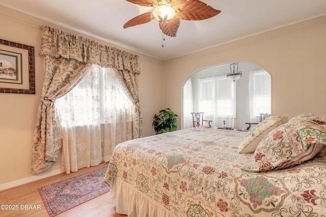 bedroom featuring light wood-type flooring, crown molding, and arched walkways