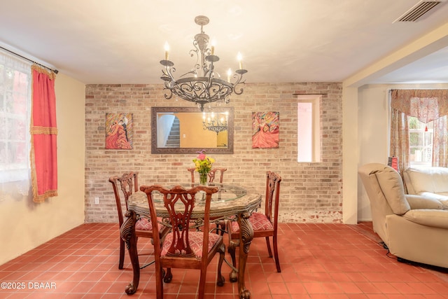 tiled dining area with brick wall, visible vents, and a notable chandelier