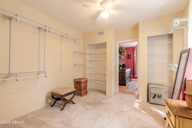 spacious closet with light carpet, visible vents, and a ceiling fan