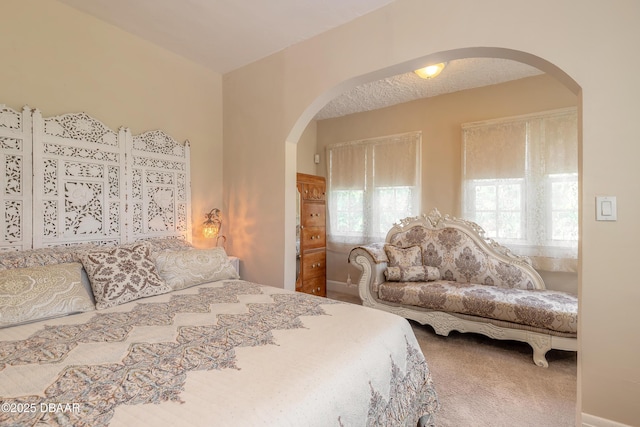 carpeted bedroom with arched walkways