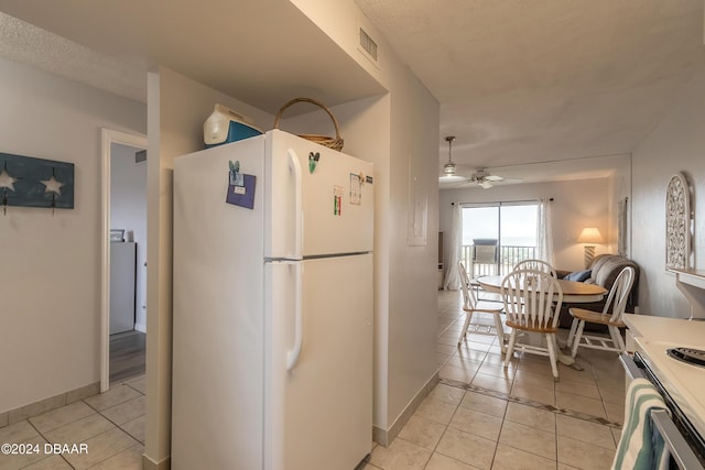 kitchen featuring ceiling fan, white fridge, stove, and light tile patterned floors