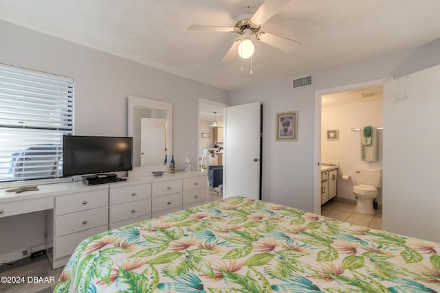 tiled bedroom with ceiling fan and ensuite bath