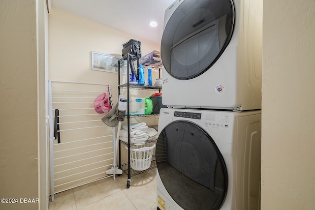 laundry area with stacked washer / drying machine and light tile patterned floors