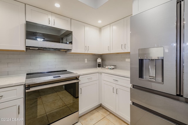 kitchen featuring stainless steel appliances, light tile patterned floors, and white cabinets