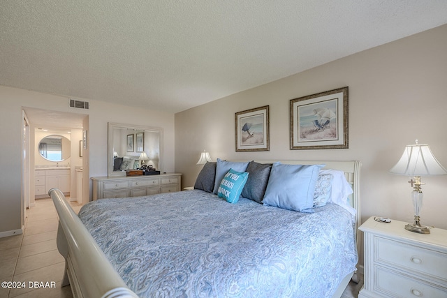 tiled bedroom featuring ensuite bathroom and a textured ceiling