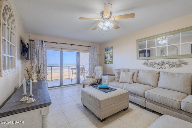 living room featuring a water view, ceiling fan, and light tile patterned floors