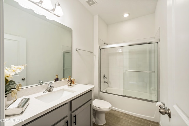 full bathroom with toilet, vanity, and bath / shower combo with glass door