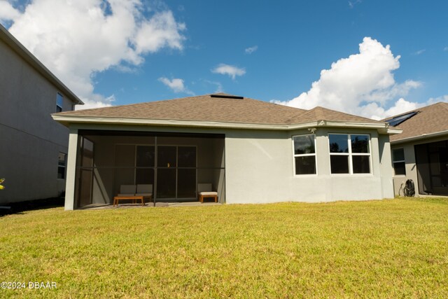 rear view of property featuring a lawn and a sunroom