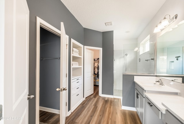 bathroom featuring wood-type flooring, vanity, a textured ceiling, and tiled shower