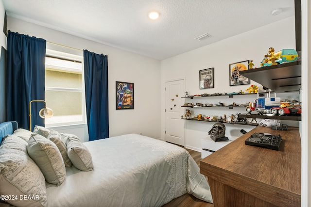 bedroom with hardwood / wood-style floors and a textured ceiling