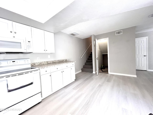 kitchen featuring visible vents, white appliances, light countertops, and baseboards