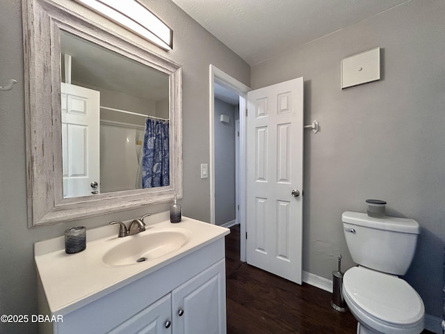 full bath with toilet, wood finished floors, a shower with shower curtain, baseboards, and vanity